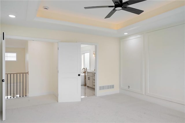 carpeted spare room with a tray ceiling and ceiling fan