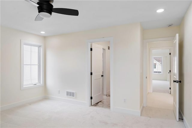 unfurnished bedroom featuring ensuite bath, light colored carpet, and ceiling fan