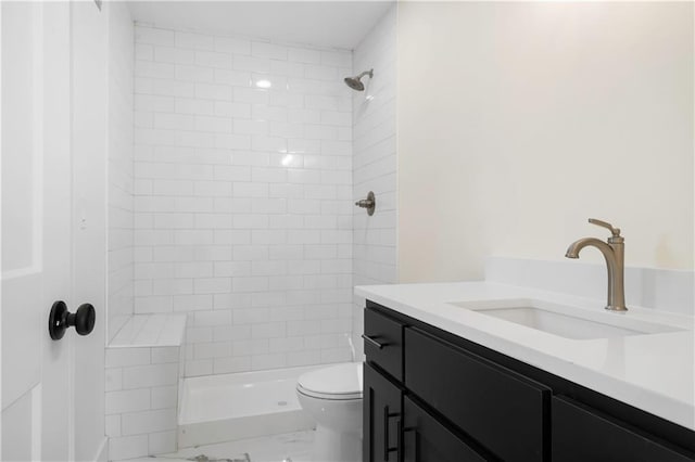 bathroom with vanity, tiled shower, and toilet