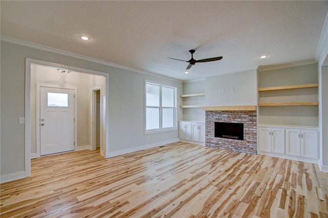 unfurnished living room featuring light hardwood / wood-style flooring, a brick fireplace, ceiling fan, and a healthy amount of sunlight