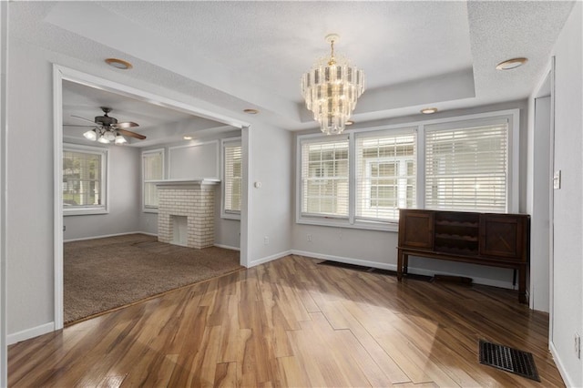 unfurnished living room with a tray ceiling, hardwood / wood-style floors, and a healthy amount of sunlight