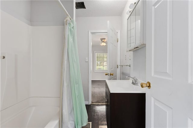 bathroom with shower / tub combo, hardwood / wood-style floors, a textured ceiling, and large vanity