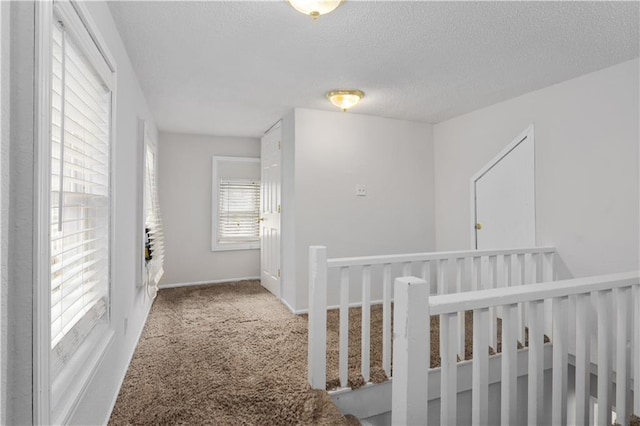 hallway featuring light colored carpet and a textured ceiling