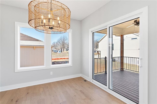 interior space featuring hardwood / wood-style flooring and ceiling fan with notable chandelier