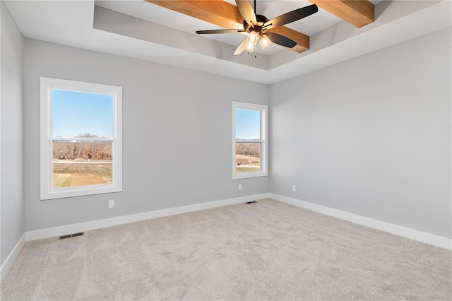 spare room featuring light carpet, beam ceiling, a raised ceiling, and ceiling fan