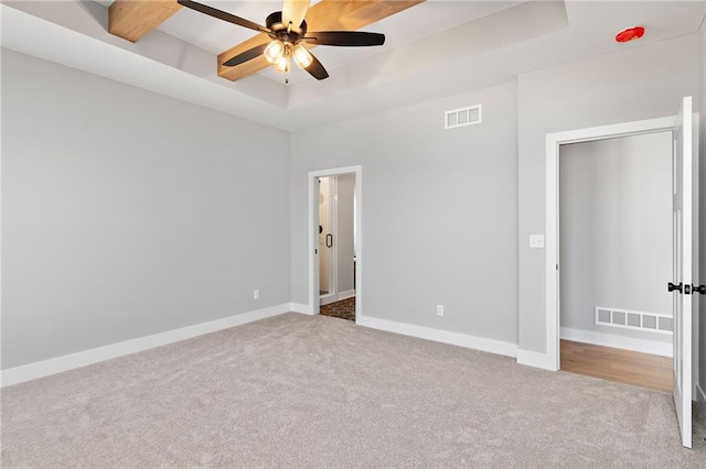 unfurnished bedroom featuring light carpet, a tray ceiling, and ceiling fan