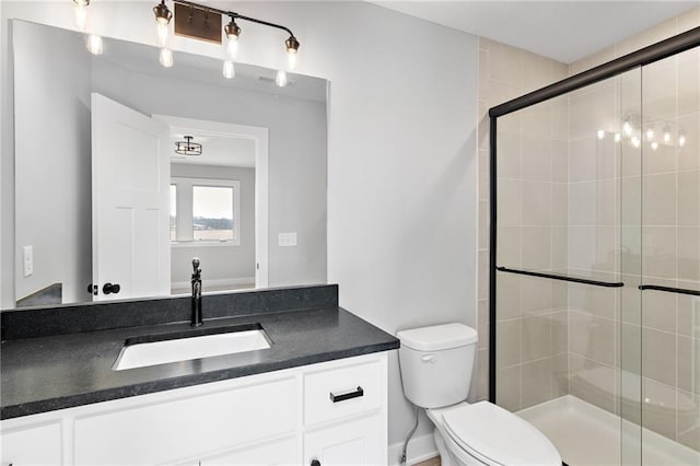 bathroom featuring vanity, a shower with shower door, and toilet