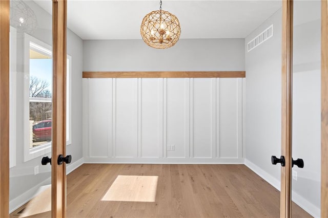 interior space featuring an inviting chandelier, light hardwood / wood-style floors, and french doors