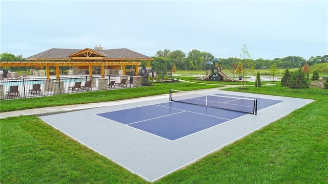 view of tennis court featuring playground community, a lawn, a community pool, and fence