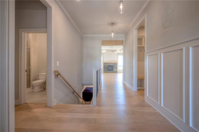 corridor with ornamental molding and light wood-type flooring