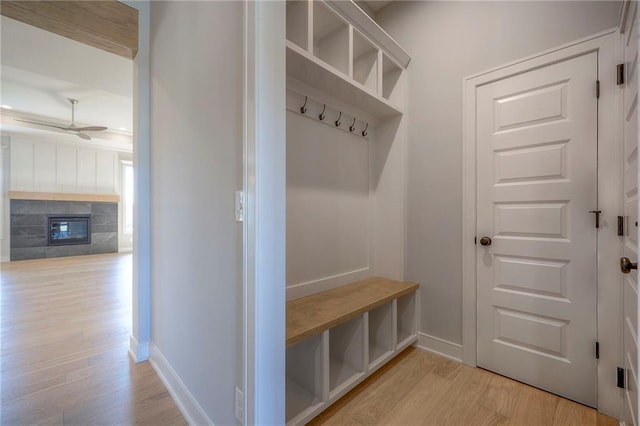 mudroom with a tiled fireplace, light hardwood / wood-style floors, and ceiling fan