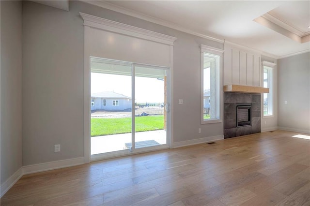 unfurnished living room with crown molding, a fireplace, light hardwood / wood-style floors, and a wealth of natural light