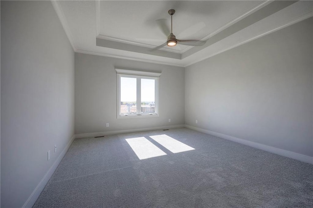 empty room with crown molding, a tray ceiling, carpet floors, and ceiling fan