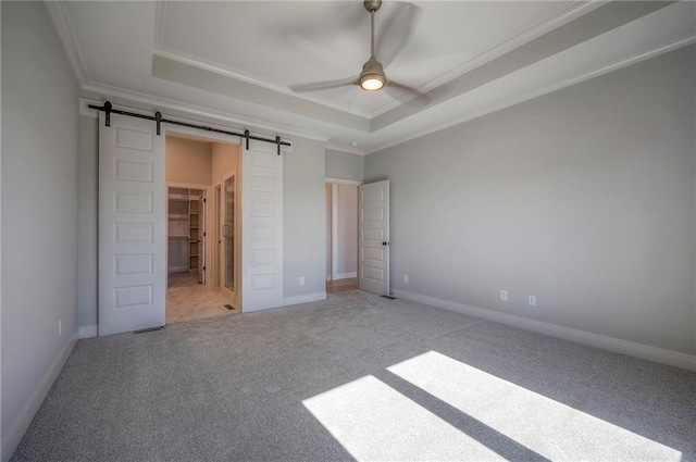 unfurnished bedroom with a raised ceiling, crown molding, a barn door, and ceiling fan