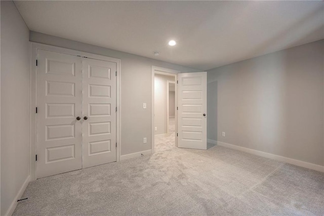 unfurnished bedroom featuring light carpet and a closet