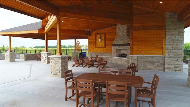 view of patio with a gazebo and an outdoor stone fireplace