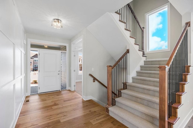 foyer with light wood finished floors, visible vents, and baseboards