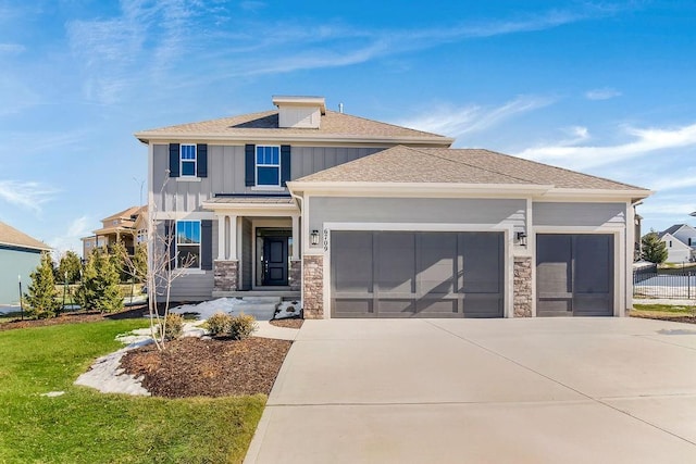 view of front of house featuring an attached garage, stone siding, driveway, a front lawn, and board and batten siding