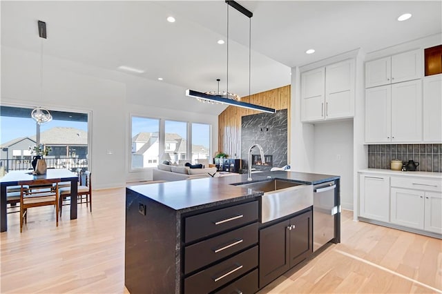 kitchen featuring dishwasher, white cabinetry, a kitchen island with sink, and sink