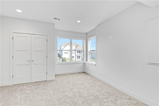 unfurnished bedroom with light colored carpet and a closet