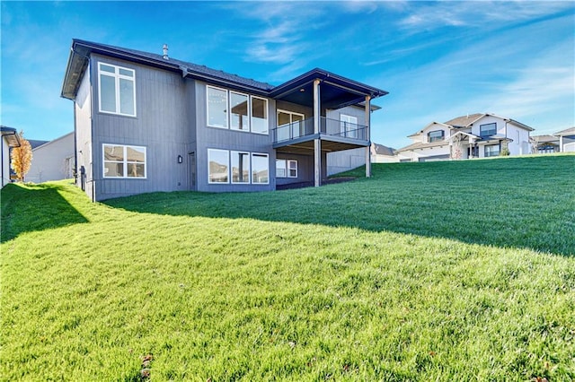 back of house featuring a balcony and a yard