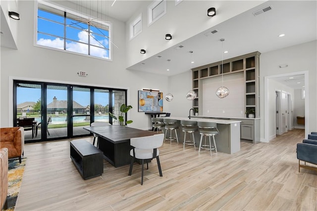 dining room with french doors, a towering ceiling, and light hardwood / wood-style floors