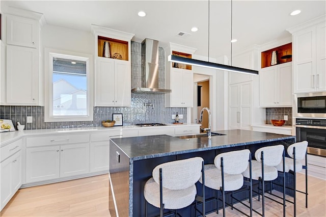 17321 Gillette St, Overland Park, KS 66221 - kitchen featuring wall chimney range hood, stainless steel appliances, backsplash, a breakfast bar, and white cabinets