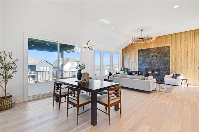 17321 Gillette St, Overland Park, KS 66221 - dining room with light wood-style flooring, wood walls, a chandelier, a fireplace, and lofted ceiling