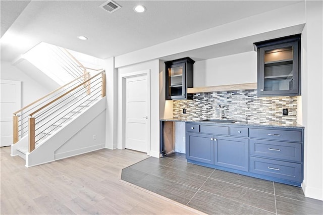 17321 Gillette St, Overland Park, KS 66221 - kitchen featuring backsplash, recessed lighting, light wood-style floors, light countertops, and glass insert cabinets