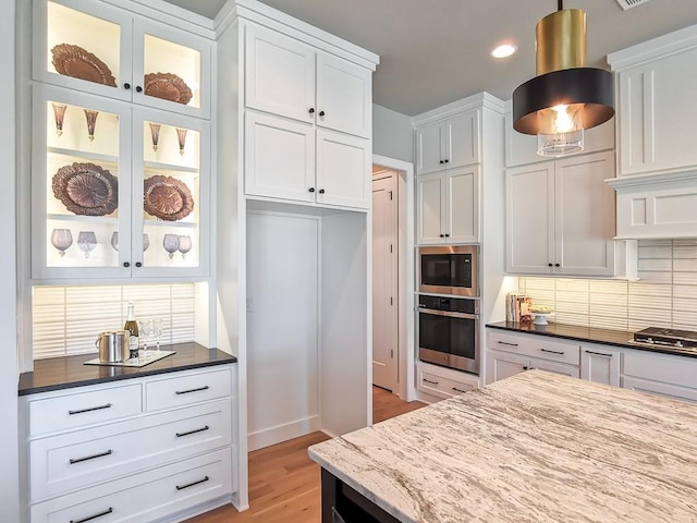 kitchen featuring white cabinetry, appliances with stainless steel finishes, tasteful backsplash, and dark stone counters