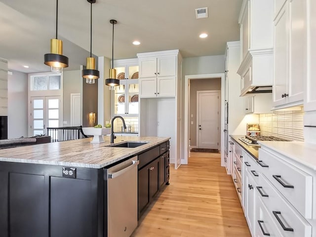 kitchen featuring stainless steel dishwasher, sink, hanging light fixtures, and white cabinets