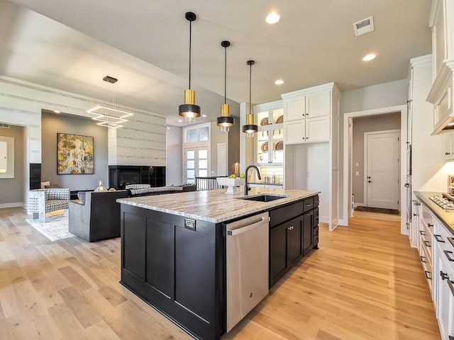 kitchen featuring sink, an island with sink, pendant lighting, stainless steel appliances, and white cabinets