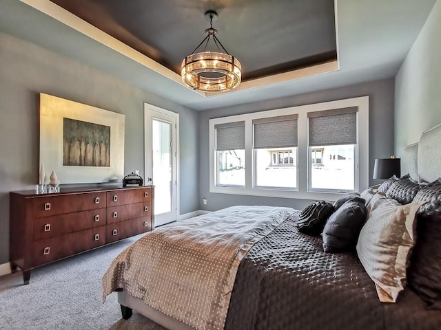 bedroom featuring an inviting chandelier, carpet flooring, and a raised ceiling