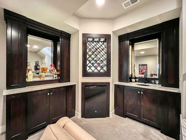 bar featuring dark brown cabinets, sink, and light colored carpet