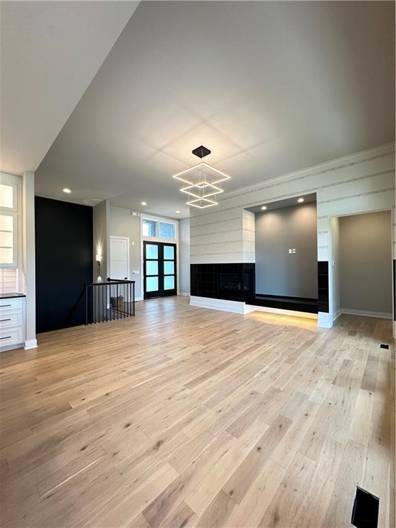 unfurnished living room with a chandelier and light hardwood / wood-style flooring