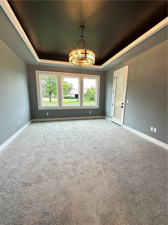 carpeted empty room with a tray ceiling