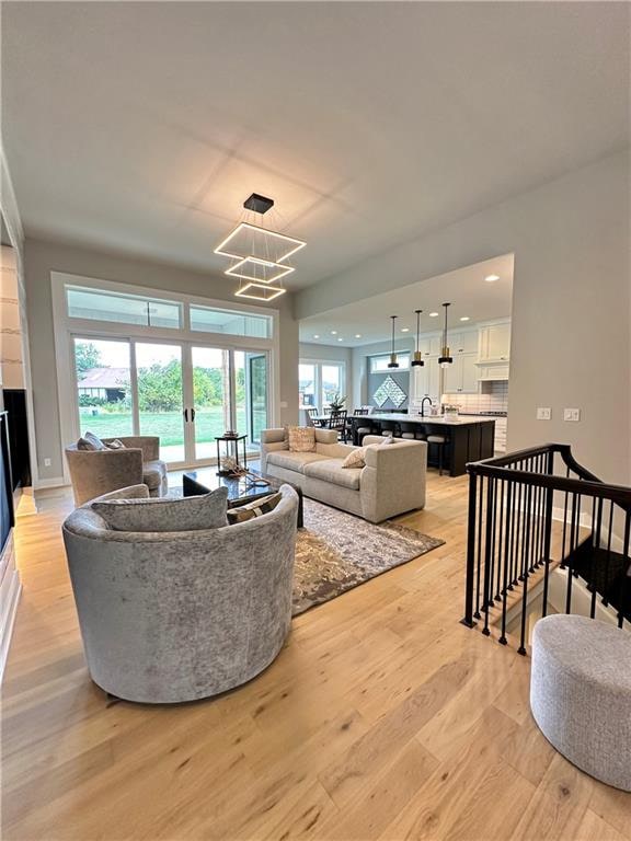 living room featuring a healthy amount of sunlight, sink, a chandelier, and light hardwood / wood-style floors