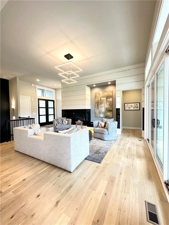 living room featuring french doors, light hardwood / wood-style floors, and a notable chandelier