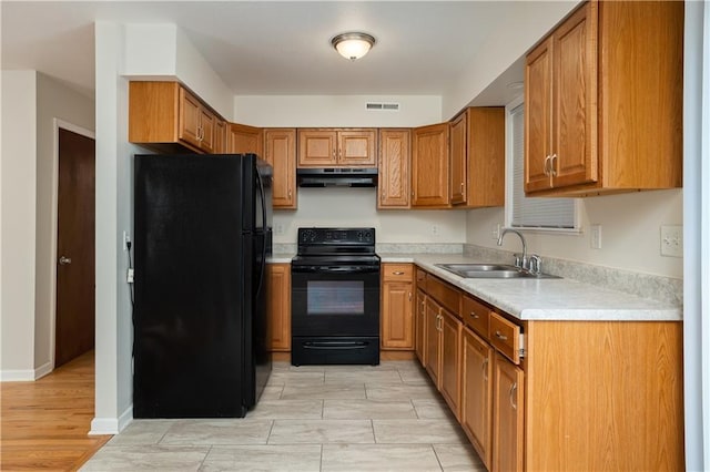 kitchen featuring light tile floors, black appliances, and sink