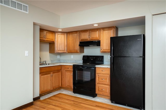 kitchen featuring light tile flooring, black appliances, and sink