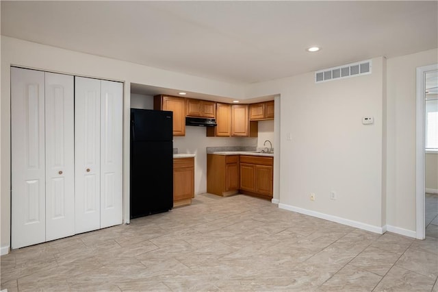 kitchen featuring black refrigerator, sink, ventilation hood, and light tile floors