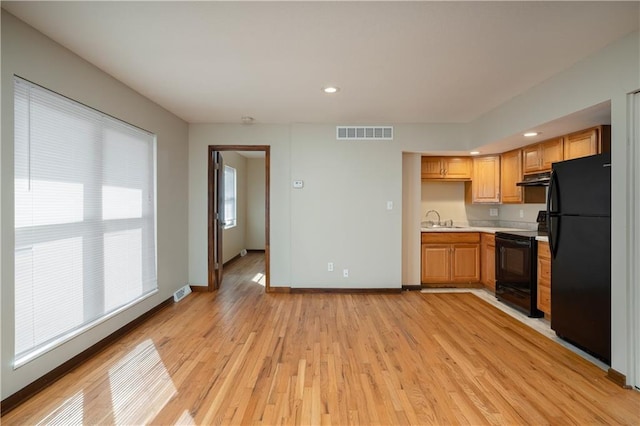 kitchen featuring black appliances, sink, and light hardwood / wood-style flooring