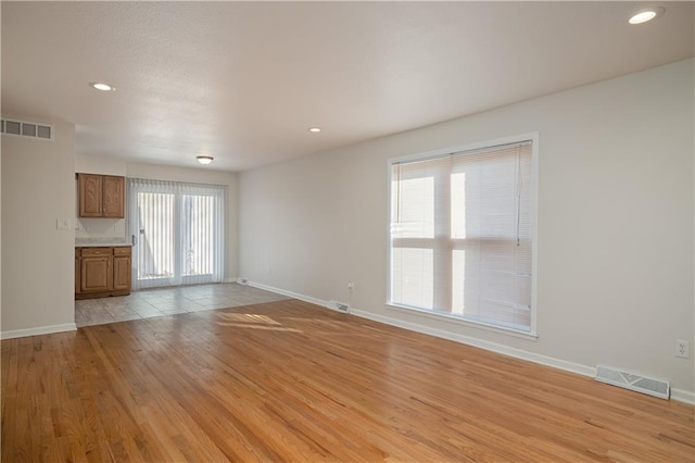 unfurnished living room featuring plenty of natural light and light hardwood / wood-style floors