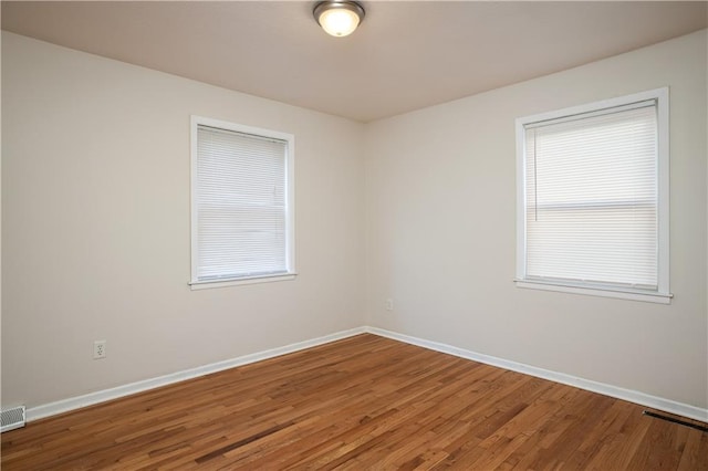 unfurnished room featuring a healthy amount of sunlight and wood-type flooring