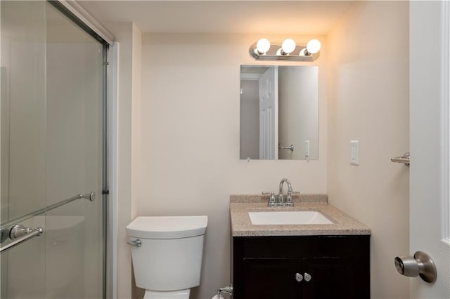 bathroom with toilet, vanity, and a shower with door