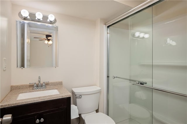 bathroom featuring a shower with door, ceiling fan, toilet, and vanity