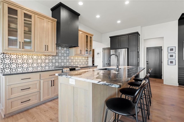 11522 S Zarda Dr, Olathe, KS 66061 - kitchen featuring dark stone counters, custom range hood, a sink, freestanding refrigerator, and light wood finished floors