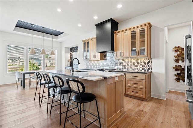 11522 S Zarda Dr, Olathe, KS 66061 - kitchen featuring a sink, a raised ceiling, baseboards, a kitchen bar, and a center island with sink