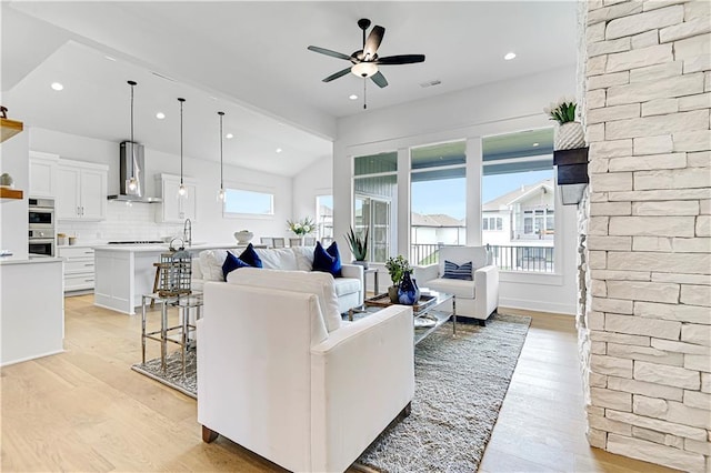 living room with light hardwood / wood-style flooring, ceiling fan, and lofted ceiling