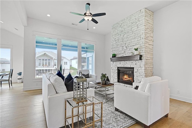 living room with a fireplace, ceiling fan, and light hardwood / wood-style floors